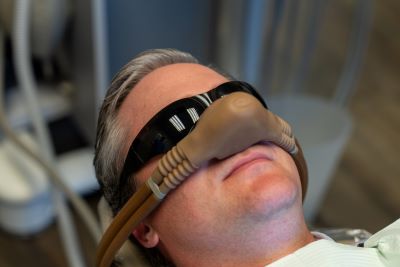 A man wearing a sedation mask over his nose, which will provide nitrous oxide during his dental procedure.