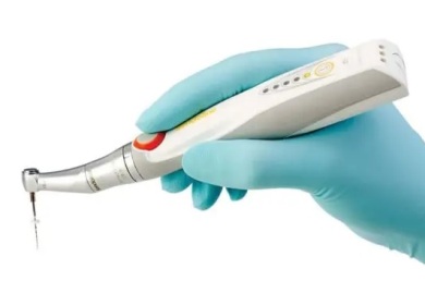 a photo of a rotary root canal handpiece being held in a gloved hand