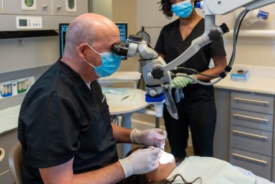 A picture of Dr. Janse performing endodontic treatment using a root canal microscope.