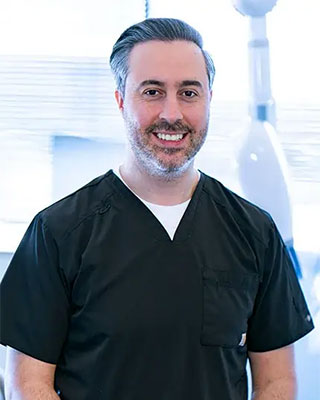 A photograph of Dr. Ahmad Rayyan, DDS. He is smiling and looking at the camera.