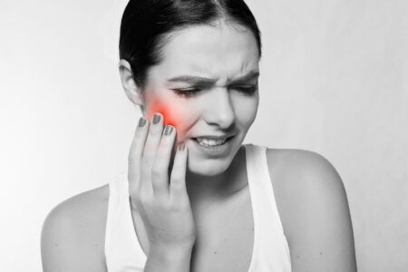 The image of a woman holding her jaw in pain. 